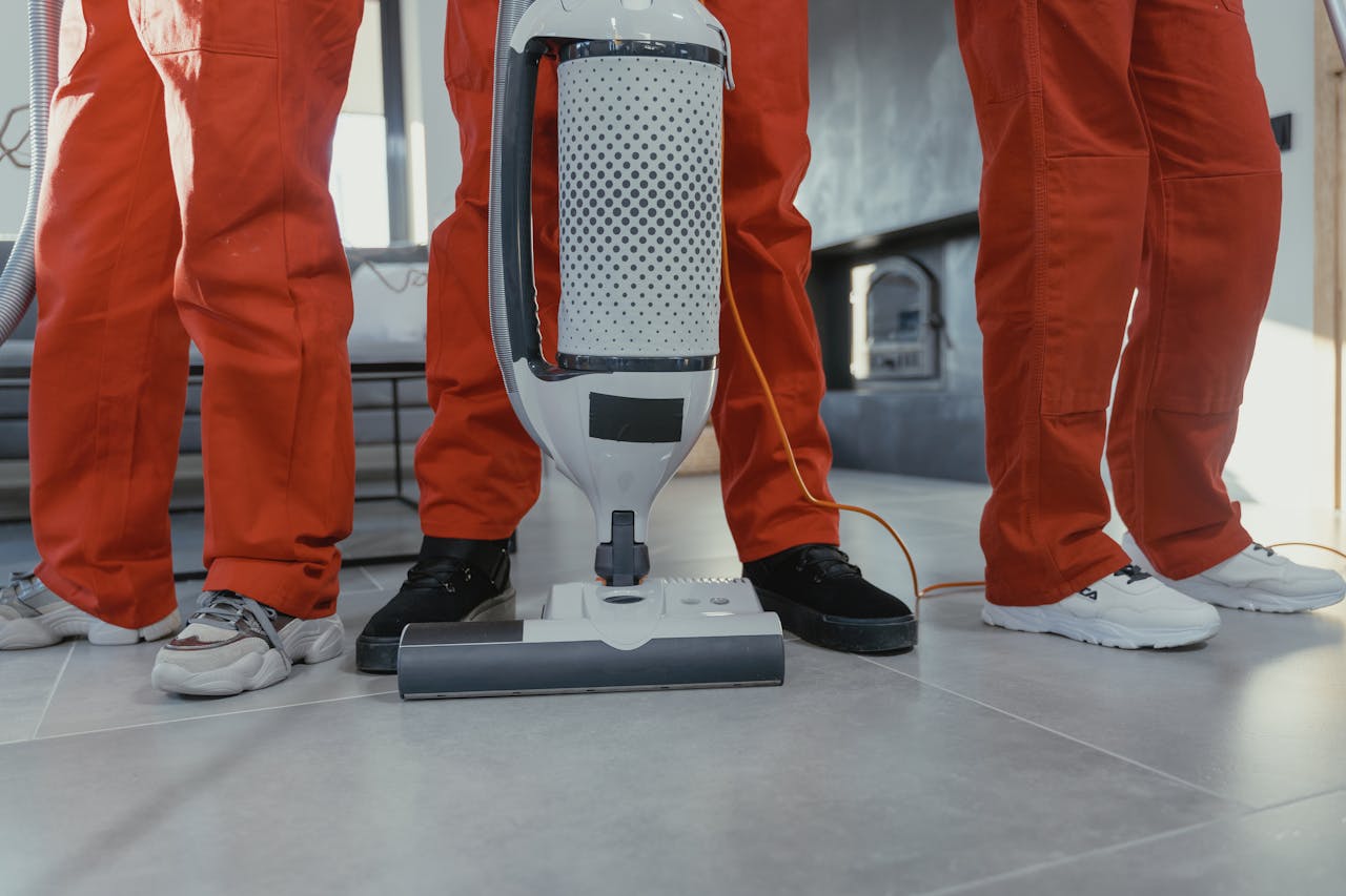 contact-img Team of professional cleaners in red uniforms using a vacuum cleaner indoors.